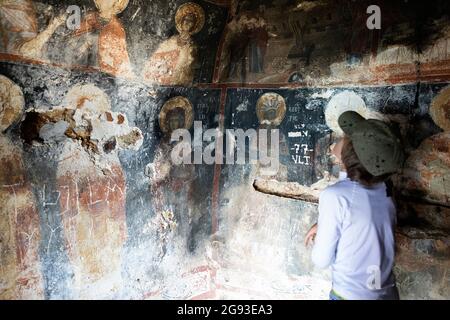 Ragazzo guardando le icone all'interno della sorprendente chiesa ortodossa grotta costruita nelle rocce sopra il lago di Prespa, Shpella e Shen Merise, Albania Foto Stock