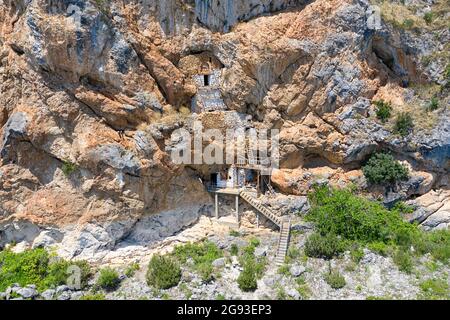Incredibile chiesa ortodossa grotta costruita nelle rocce sopra il lago di Prespa, Albania Foto Stock