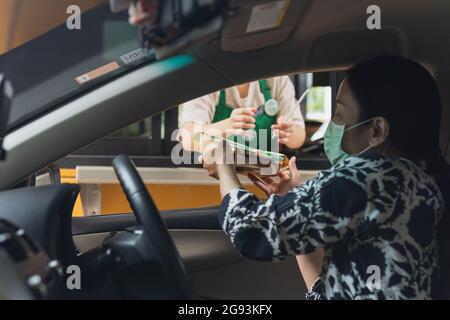 Bangkok THAILANDIA - 23 luglio 2021; il cliente Donna preleva il cibo allo Starbuck Cafe Drive Through. Foto Stock