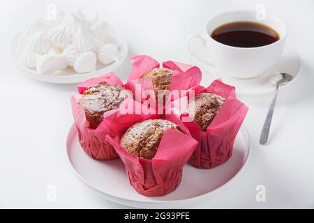 Muffin, marshmallows e caffè nero su un tavolo bianco. Foto Stock