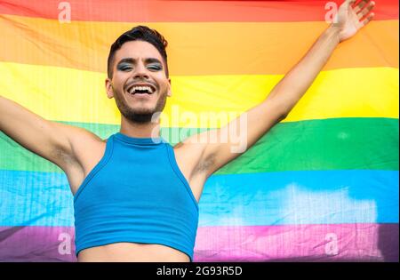 Felice uomo omosessuale che celebra l'orgoglio gay che tiene la bandiera arcobaleno simbolo della comunità LGBTQ Foto Stock