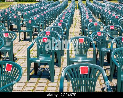 File di sedie verdi vuote in plastica a Roses Park, Timisoara. Sedie per concerti all'aperto, festival e altri eventi. Foto Stock