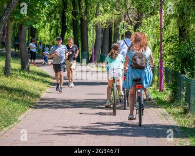 Timisoara, Romania - 06.19.2021: Scena estiva da Roses Park (Parcul Rozelor) con persone a cavallo biciclette e jogging Foto Stock