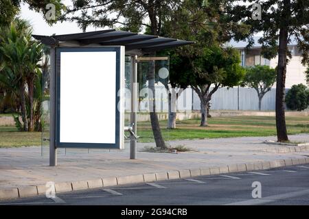 Cartellone bianco verticale sulla strada della città con alberi verdi Foto Stock