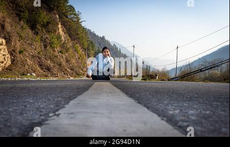 giovane ragazza in piedi al centro della strada asfaltata da basso angolo al mattino Foto Stock