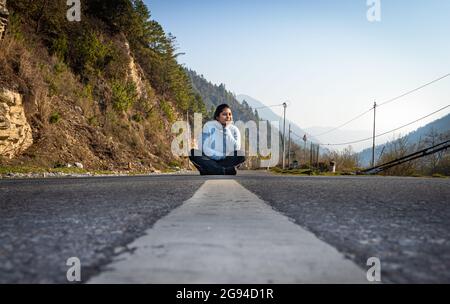 giovane ragazza in piedi al centro della strada asfaltata da basso angolo al mattino Foto Stock