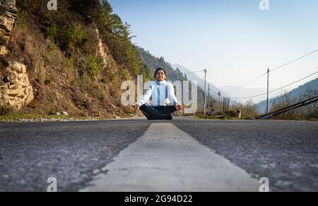 giovane ragazza in piedi al centro della strada asfaltata da basso angolo al mattino Foto Stock