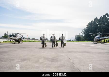 tre uomini militari che camminano su una pista verso gli elicotteri Foto Stock