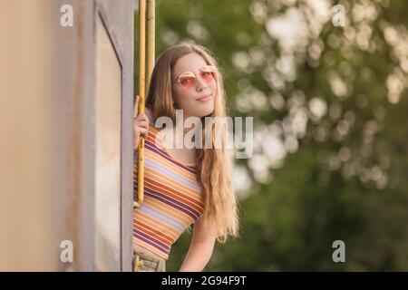 Ragazza anni '70 stile retrò in occhiali rosa sul treno Foto Stock