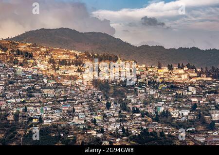 la vista dell'urbanizzazione della città dalla cima della collina con una costruzione enorme e un'immagine drammatica del cielo è presa a bomdilla arunachal pradesh india. Foto Stock