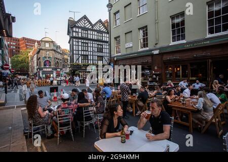 Le persone che godono di cibo e bevande all'aperto nel centro di Londra come Covid restrizioni sono attenuate in Old Compton Street , Soho, Londra , Regno Unito . Foto Stock