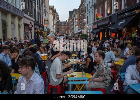 La gente mangia sui tavoli del ristorante posti fuori Frith Street, Soho, Londra, Regno Unito. Foto Stock