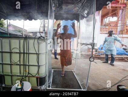 Nonthaburi, Tailandia. 24 luglio 2021. Un monaco buddista cammina attraverso una cabina di disinfezione presso un crematorio durante una cerimonia funeraria a Wat Bang Muang, nella provincia di Nonthaburi, alla periferia di Bangkok. Finora la Thailandia ha confermato 481,967 casi di Coronavirus con 327,789 casi recuperati e 3,930 decessi. (Foto di Chaiwat Subprasom/SOPA Images/Sipa USA) Credit: Sipa USA/Alamy Live News Foto Stock