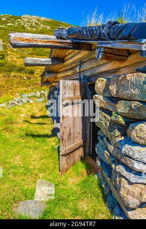 Incredibile vecchia casa in pietra a Vavatn paesaggio vista panoramica con montagne con neve durante l'estate in Norvegia Hemsedal. Foto Stock