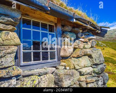 Incredibile vecchia casa in pietra a Vavatn paesaggio vista panoramica con montagne con neve durante l'estate in Norvegia Hemsedal. Foto Stock