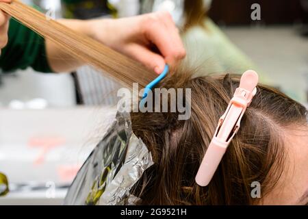 Tintura dei capelli durante il periodo di quarantena, cliente e parrucchiere in maschere, decolorazione dei capelli. Novità Foto Stock