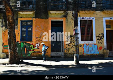 Lonesome cowboy camminare per le strade di Santa Teresa un quartiere con colorati murales Street art a Rio de Janeiro, Brasile. Foto Stock