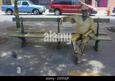 Statua del compositore portoricano Tite Curet Alonso seduto su una panchina in Plaza de Armas, Old San Juan, Porto Rico, USA. La statua di Luz Badillo Foto Stock