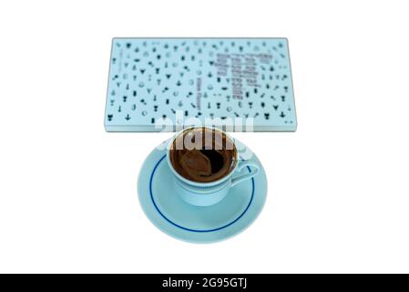 Libro chiuso e tazza di caffè turco su sfondo bianco Foto Stock