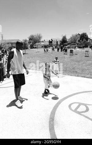 JOHANNESBURG, SUDAFRICA - 06 gennaio 2021: Un colpo in scala di grigi dei bambini africani che fanno un tiro di obiettivo sul campo di pallacanestro pubblico del parco giochi Foto Stock