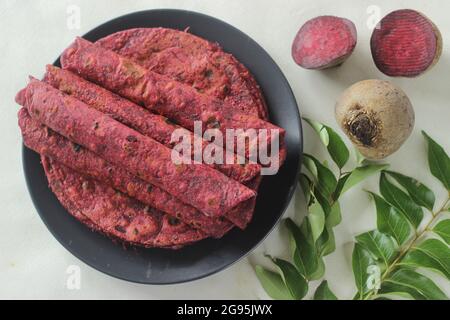 La barbabietola Paratha è un pane piatto di grano integrale fritto in padella indiana fatto di farina di grano impastata con barbabietole grattugiate fresche e spezie. Girato su sfondo bianco Foto Stock