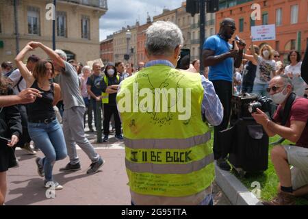 Gilet Jaune (Yellow Vest) protetore con l'iscrizione 'i'll be back', tra le persone che ballano. Il 24 luglio 2021, diverse migliaia di persone hanno sfidato il divieto prefetturale di dimostrare per la quarta volta, marciando per le strade di Tolosa (Francia). Cantando la parola "libertà", e gli slogan anti-Macron, i manifestanti hanno marciato sui viali del centro della città, protestando così contro il Passo sanitario e un obbligo di vaccinazione che non avrebbe detto il suo nome. Foto di Patrick Batard / ABACAPRESS.COM Foto Stock