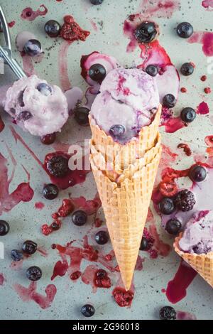 Fondendo il gelato alla bacca adagiato in un cono di waffle Foto Stock