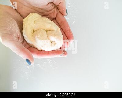 Le mani trattengono l'impasto intrecciato in treccia Foto Stock