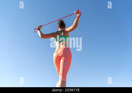 donna che si esercita all'aperto con fasce di gomma Foto Stock