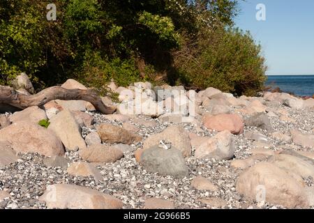 Molti massi sulla spiaggia di Rrügen con arbusti verdi, mare e cielo blu sullo sfondo. Foto Stock