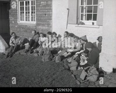 Anni '50, storico, un gruppo di rambler seduti havng uno spuntino, prendendo una pausa dalla loro passeggiata a sud Downs, Sussex est, Inghilterra, Regno Unito. Conosciuta per Beachy Head, la più alta scogliera di mare di gesso in Gran Bretagna, le ondeggianti South Downs sono un luogo famoso per le passeggiate di piacere. Un'area di straordinaria bellezza naturale, nel 1929, un atto del Parlamento ha permesso l'acquisto della terra per salvaguardarne l'uso per le generazioni future. Foto Stock