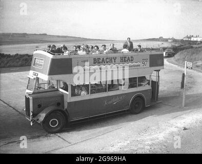 Anni '50, storica, 'Visit Beachy Head'....persone su un autobus scoperto a due piani, un'utility Guy Arab', servizio 97, parcheggiato a Beachy Head, un promontorio sul South Downs a Eastbourne, East Sussex. La più alta scogliera di mare di gesso in Gran Bretagna, i suoi dintorni ondulati discese è un luogo famoso per il piacere di camminare, con vista sul canale Inglese. Un'area di straordinaria bellezza naturale, nel 1929, la terra è stata acquistata per salvaguardarne l'uso per le generazioni future. Southdown Motors ha gestito la Route 97 dalla Royal Parade alla cima di Beachy Head, un servizio per gli escursionisti che risale alla prima guerra mondiale. Foto Stock