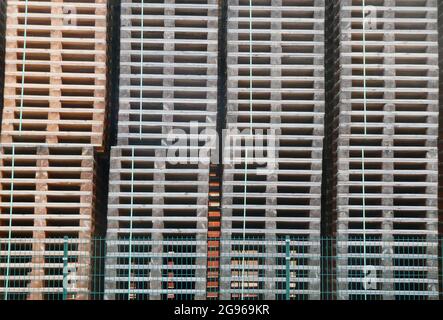 Grandi pile di pallet impilate ordinatamente in un sito di fabbrica. Foto Stock