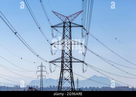 Poli elettrici che trasportano elettricità ad alta tensione Foto Stock