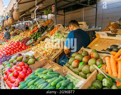 Vendor presso la mostra con frutta e verdura fresca al mercato all'aperto Sennoy, il più economico a San Pietroburgo, Russia Foto Stock