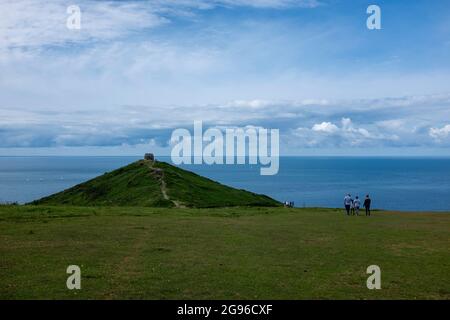 I turisti camminano da e per la Cappella di Rame Head attraverso un promontorio roccioso Foto Stock