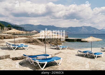 Spiaggia acciottolata con lettini e ombrelloni vicino al mare Foto Stock