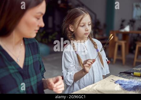 Negozio Flourist con diversi tipi di fiori bevuti. Giovane specialista felice sicuro sta lavorando con il suo capretto femminile. Foto Stock