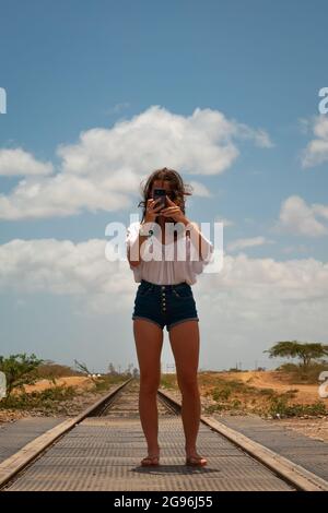 Uribia, la Guajira, Colombia - Maggio 28 2021: Donna caucasica scatta una foto sulle tracce vuote del treno Foto Stock