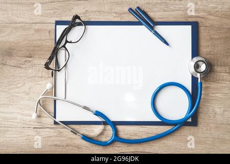 scheda medica del paziente primo piano, uno stetoscopio e pillole sulla scrivania del medico Foto Stock