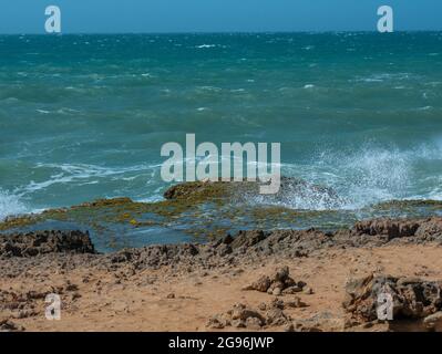 White Spume conosciuto come Sea, Ocean o Beach foam creato dall'agitazione di acqua di mare sopra le rocce della costa Foto Stock