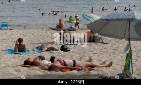 Calvia, Spagna. 24 luglio 2021. Gli ospiti si trovano sulla spiaggia di Paguera a Maiorca. Dopo l'annunciato passaggio della Spagna all'area ad alta incidenza di Corona, inizialmente non ci sono indicazioni che un maggior numero di persone voglia annullare le proprie vacanze a Maiorca prematuramente o annullare i soggiorni prenotati. Credit: Clara Margais/dpa/Alamy Live News Foto Stock