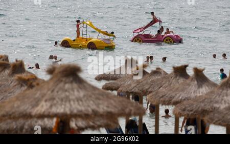 Calvia, Spagna. 24 luglio 2021. Gli ospiti si divertono sulle loro pedalò sulla spiaggia di Paguera a Maiorca. Dopo l'annunciato passaggio della Spagna all'area ad alta incidenza di Corona, inizialmente non ci sono indicazioni che un maggior numero di persone voglia annullare le proprie vacanze a Maiorca prematuramente o annullare i soggiorni prenotati. Credit: Clara Margais/dpa/Alamy Live News Foto Stock