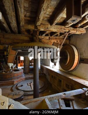 Pietre di mulino di acqua e ingranaggi all'interno di un mulino di pavimento Foto Stock