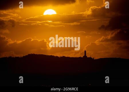 Tramonto sulla spiaggia di Loredo nel comune di Somo in provincia di Santander, con vista sul faro e le grandi nuvole Foto Stock