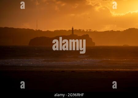 Tramonto sulla spiaggia di Loredo nel comune di Somo in provincia di Santander, con vista sul faro e le grandi nuvole Foto Stock