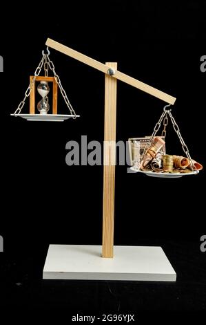 Colpo verticale della macchina equilibratrice che mostra il peso del tempo e del denaro. Foto Stock