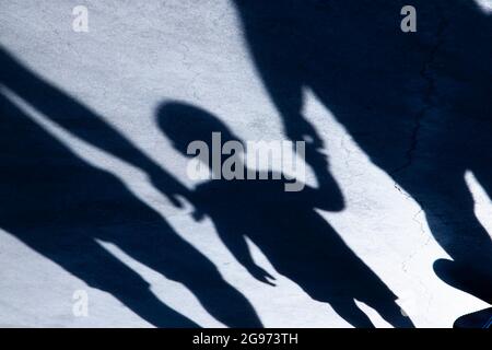 Silhouette ombra sfocata di un ragazzino che cammina con i genitori in mano nella notte Foto Stock