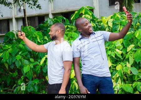 due amici maschi africani si sostengono e scattano insieme foto o selfie Foto Stock