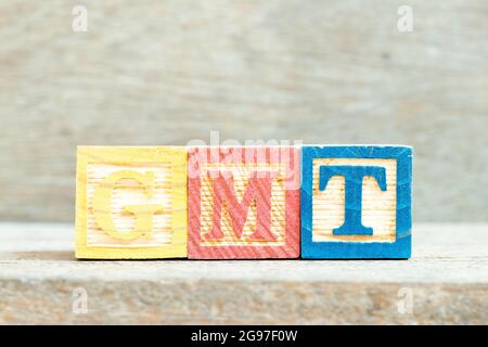 Blocco di lettere alfabetiche a colori in GMT di parola (Abbreviazione di Greenwich Mean Time) su sfondo di legno Foto Stock